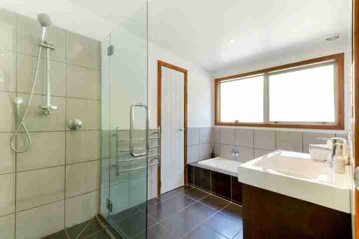 Modern bathroom at Karaka Sanctuary with bathtub, large shower and sink