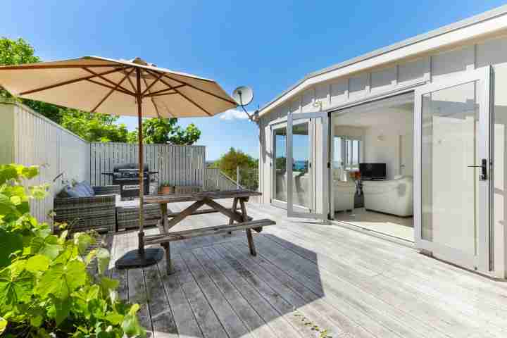 Outdoor dining and BBQ area on large deck at Tiri Cottage, Oneroa accommodation