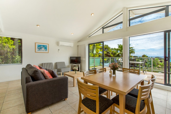 Lounge and dining area onto deck in modern apartment at The Resort, Waiheke